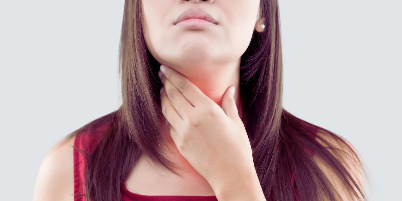 Long-haired lady feeling her neck with her right hand